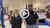 two people standing in front of a car in a garage